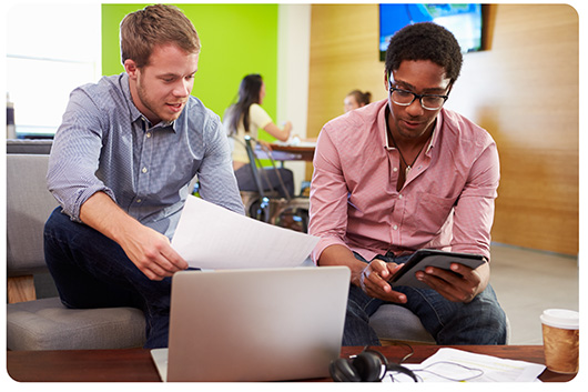 Two young men working together in an office with a laptop