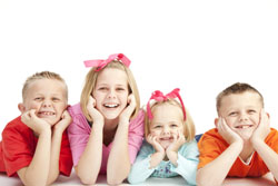 kids laying on stomach, with hands on cheeks, smiling