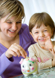 mom and daughter put money in piggy bank